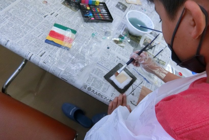 板に絵の具で絵を描いている