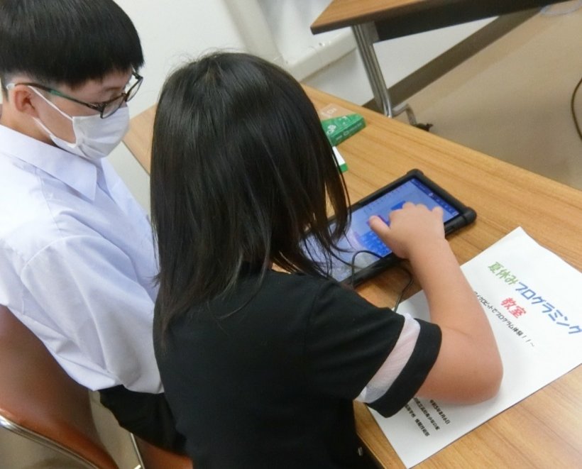 タブレットにプログラミングしている2人