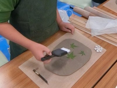 お皿の葉っぱとはけで模様をつけている