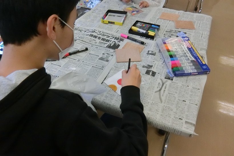 板に絵の具で絵を描いている