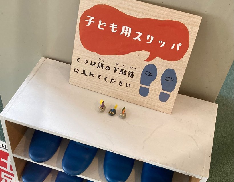 子供用スリッパ入れと石でできたオタマジャクシ