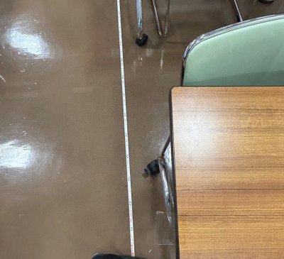 机の足元にメジャーを引っ張っている