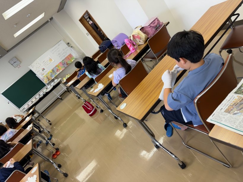 机に座って和紙を折っている