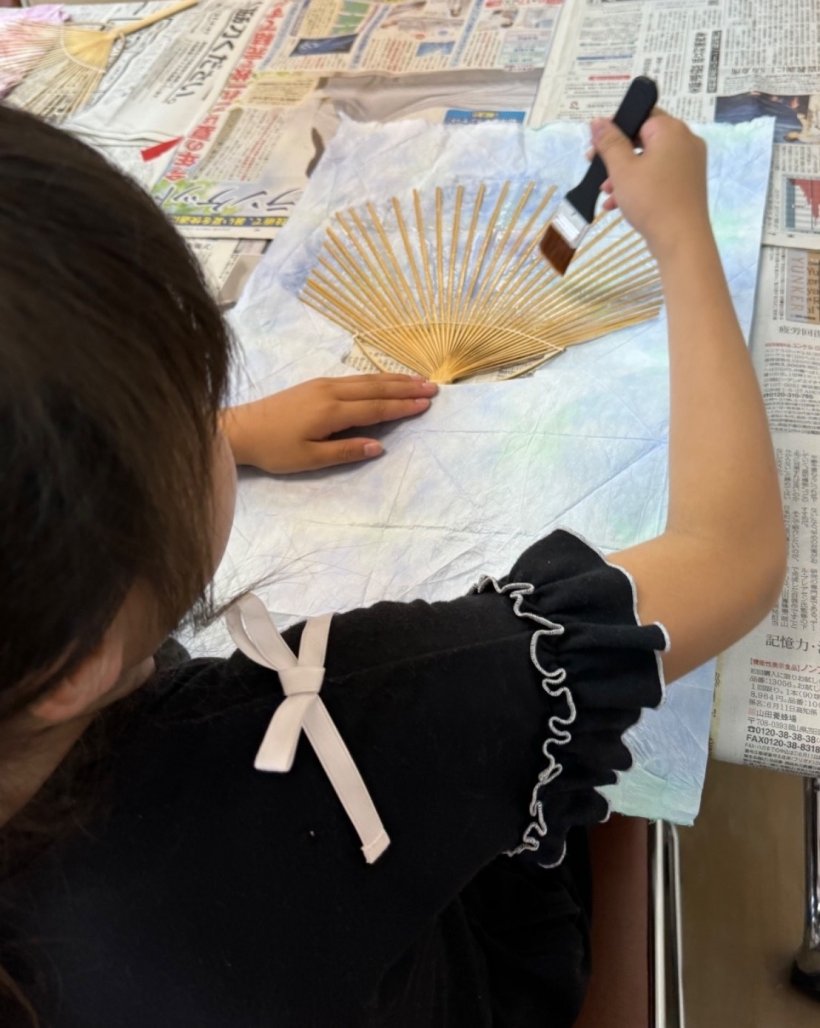 うちわの骨にノリを塗っている