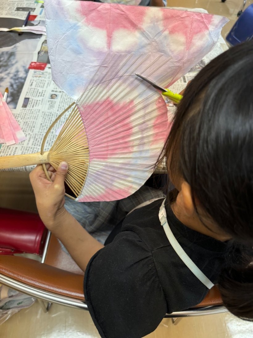 うちわの形にハサミで切っている