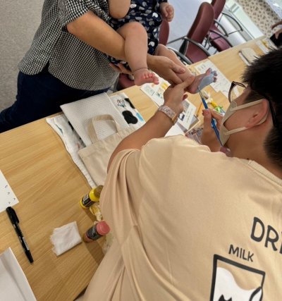 お父さんが子どもの足裏に絵の具を塗っている