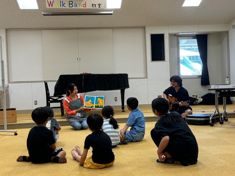 ギターを弾いている人、絵本を読み聞かせをしている