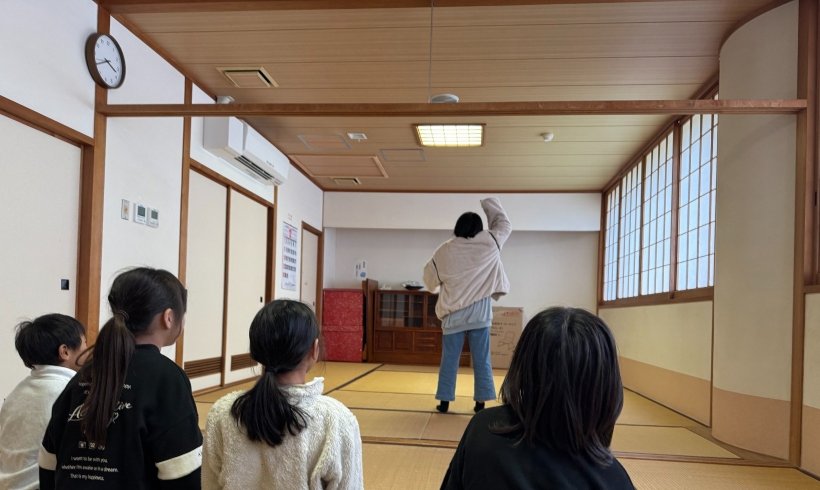 ジェスチャーしているのを4人が座ってみている