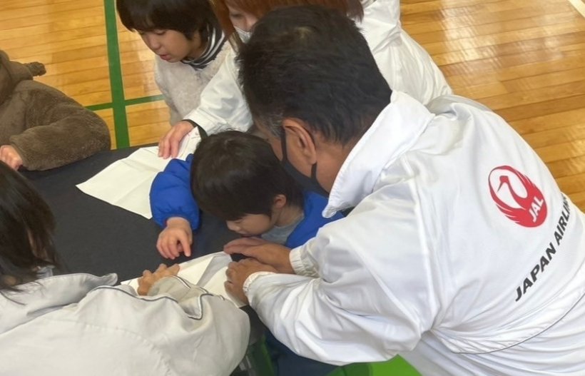 紙ヒコーキの折り方を教えている