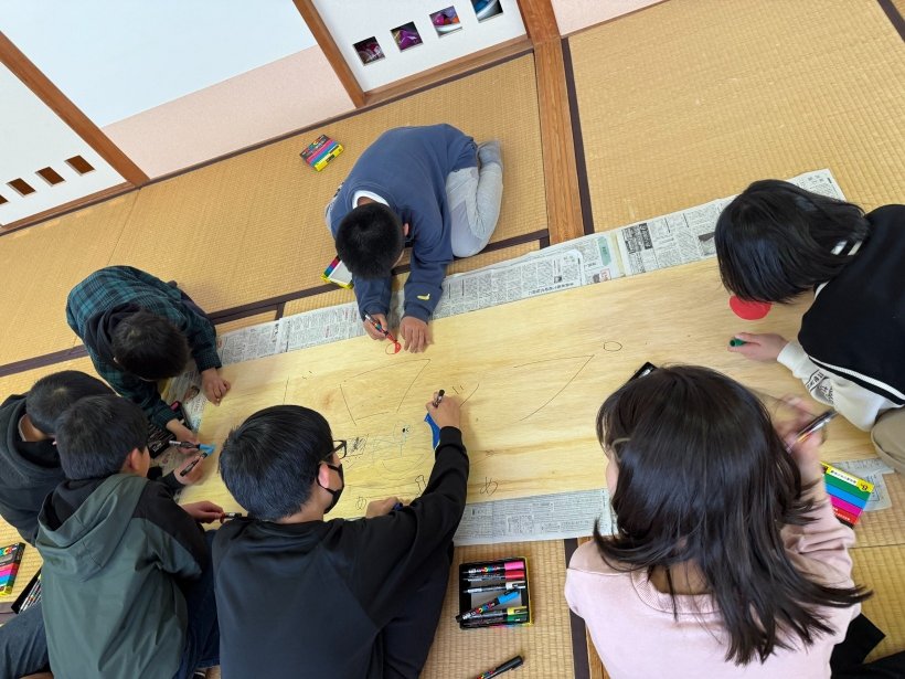 板にみんなで絵を描いている