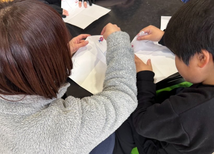 大人と子供が一緒に折り紙を折っている