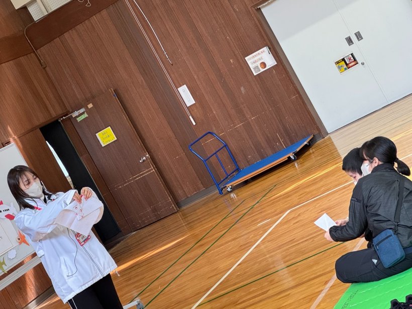 前で1人・座って大人と子供がそれぞれ折り紙を折っている