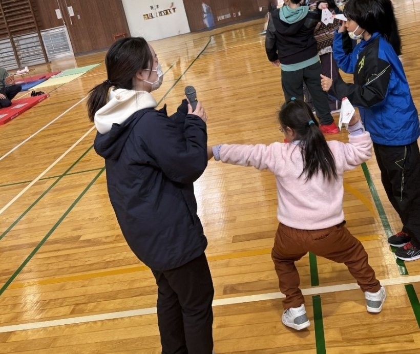 マイクを持っている人・紙ヒコーキを投げているこどもたち