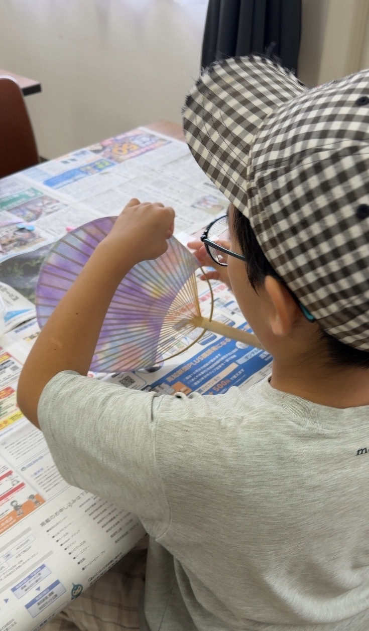 うちわに和紙を張り付けている