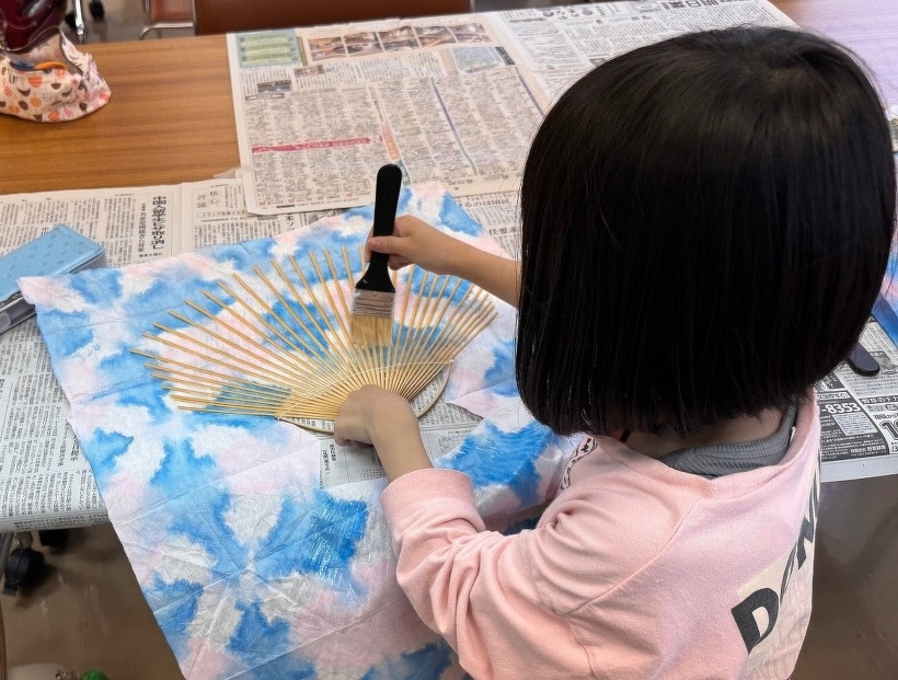 うちわの骨にのりを筆でぬっている