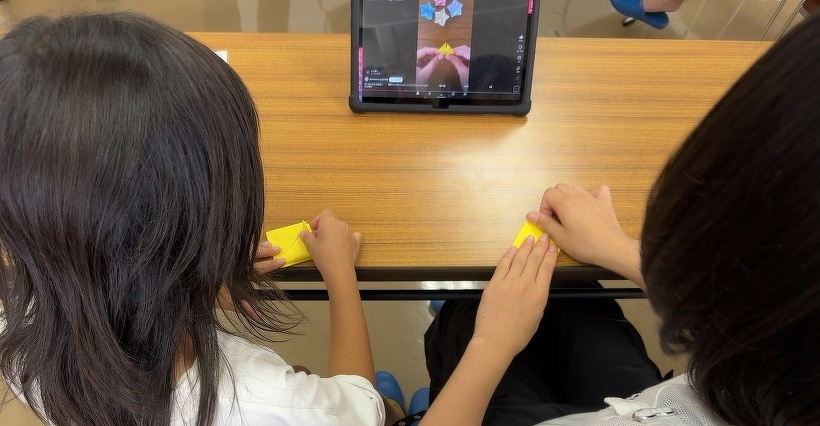 タブレットを見ながら2人で折り紙を折っている