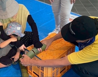 お母さんと協力して竹をきる子ども