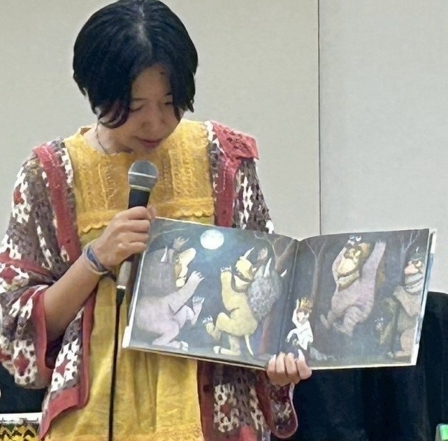 マイクを持って絵本を読んでいる