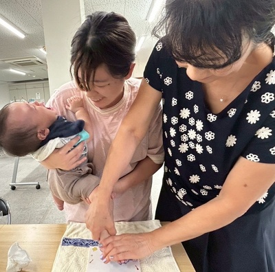 足形を押す川田真由美先生と泣いている子どもを抱える保護者