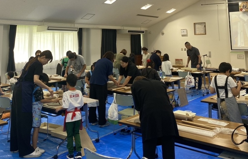 親子陶芸教室の会場となった大集会室で、参加者が立って粘土をこねている会場全体の様子。