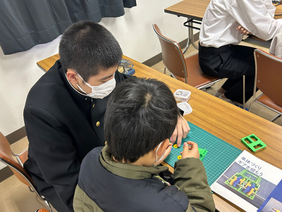 参加者の小学生が高校生と一緒に車体の内部パーツを組んでいる様子