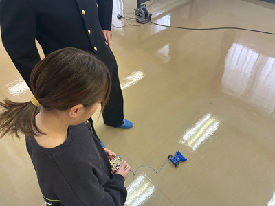 参加者の小学生が作った車型ロボットを操作して動かしている様子