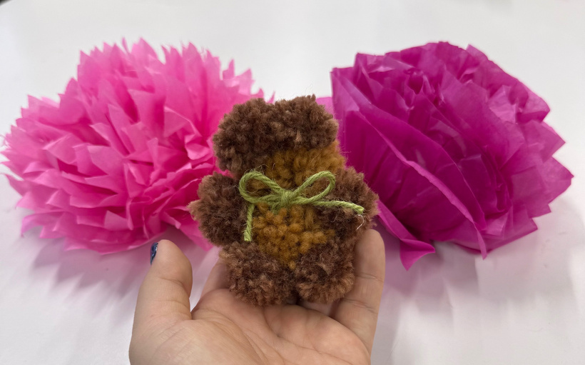 花の間に毛糸でできたクマをもっている