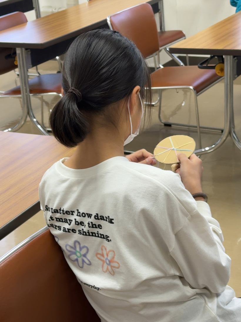 丸いダンボールでミサンガを作っている