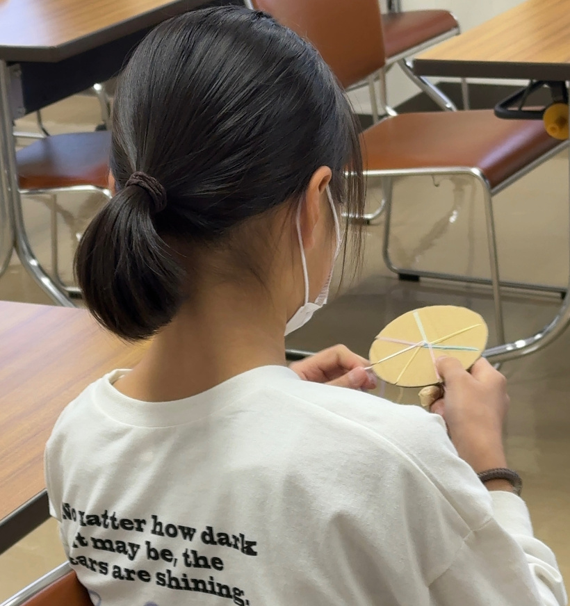 段ボールキットでミサンガを編んでいる