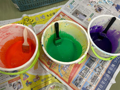 オレンジ、緑、紫の絵の具を入れた3つのバケツ