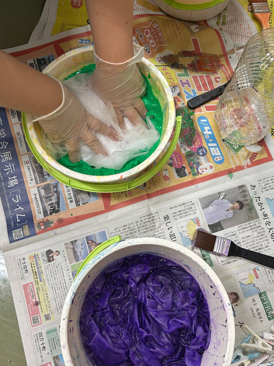 緑の染料が入ったバケツに不織布を浸けている様子