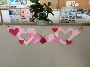 画用紙で作った赤やピンクのハートが並んだガーランド風の飾り