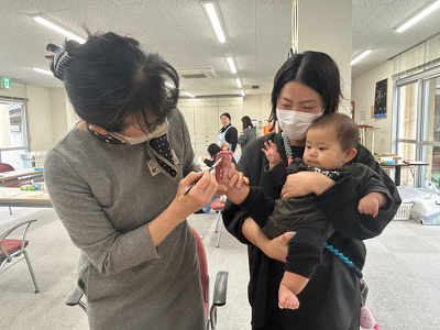 川田先生が子どもの足の裏に絵の具を塗っている