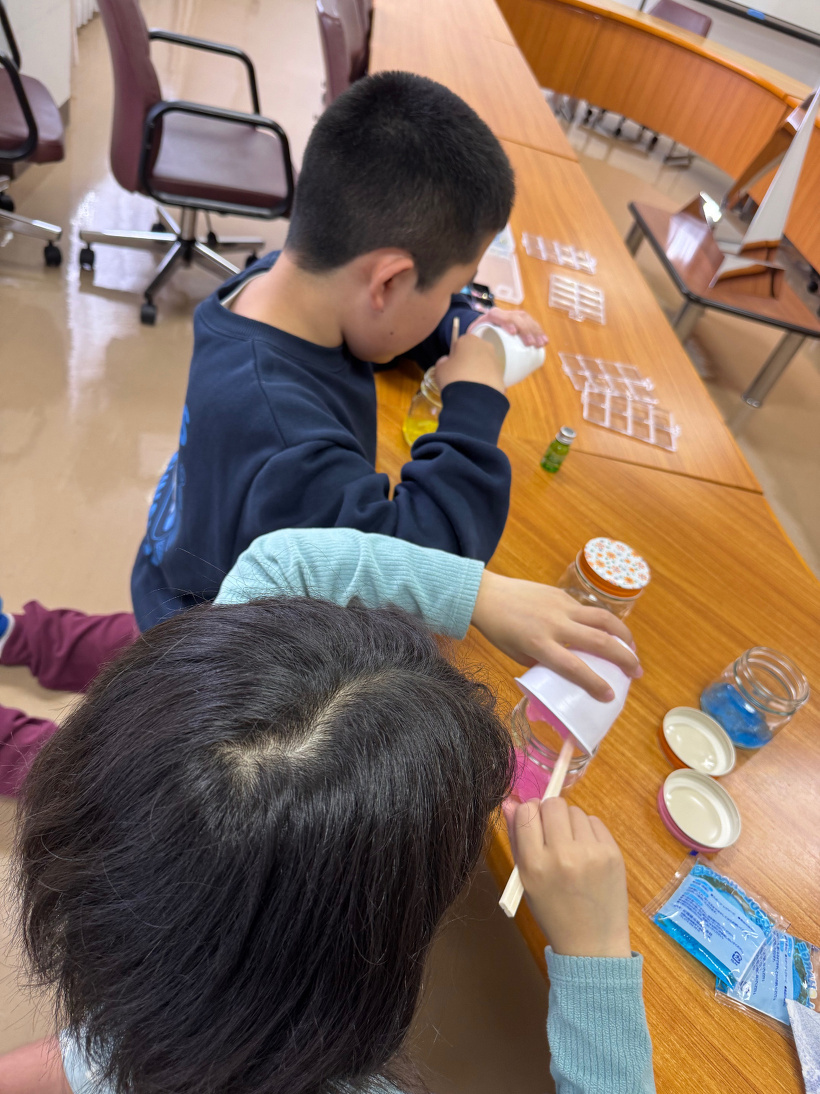 2人が色を付けた保冷剤をビンに入れている