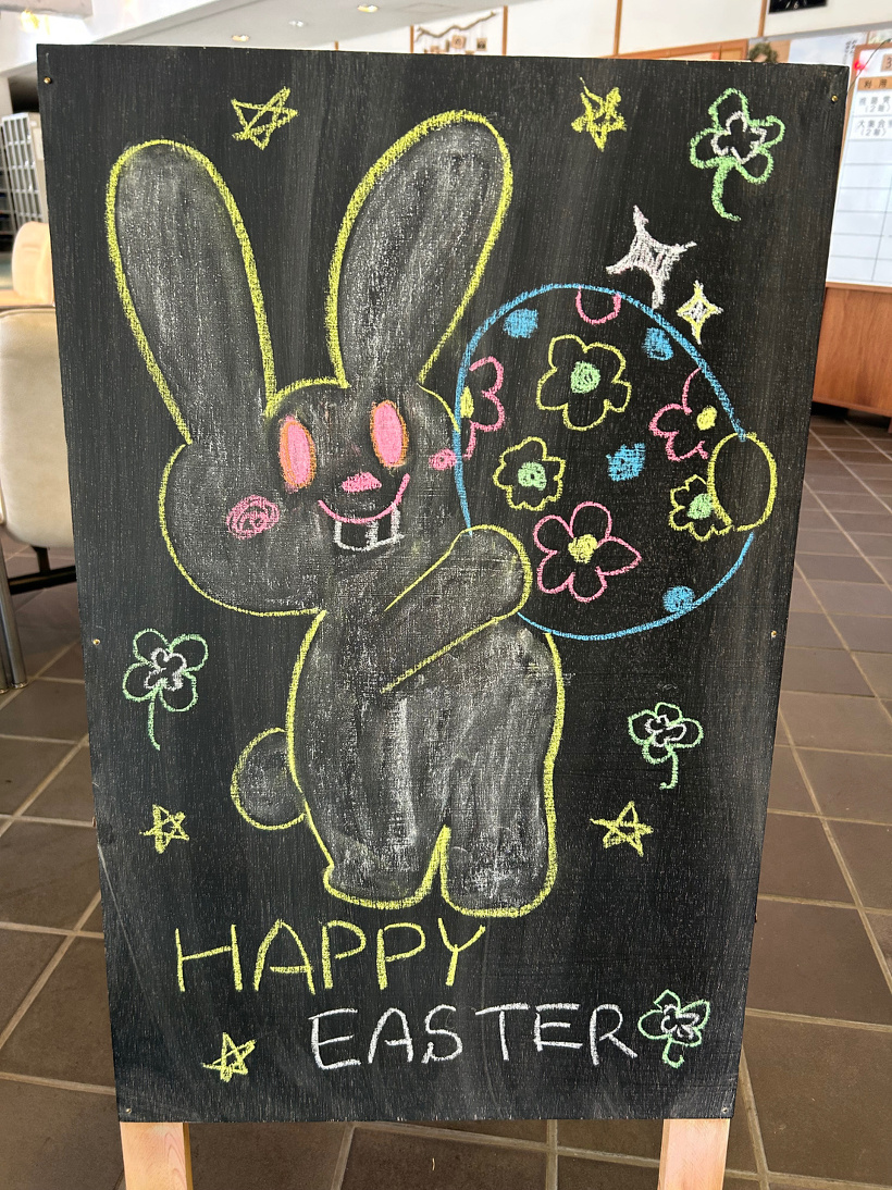 黒板の立て看板に描かれたうさぎとイースターエッグの絵