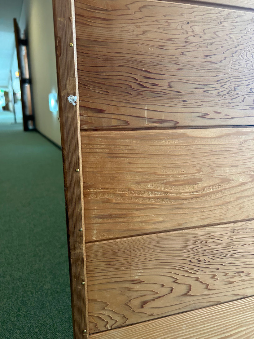 会議室の木製のドアを釘を打って修理した様子