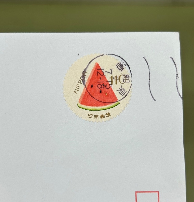 郵便物の切手にカットされたスイカが描かれている