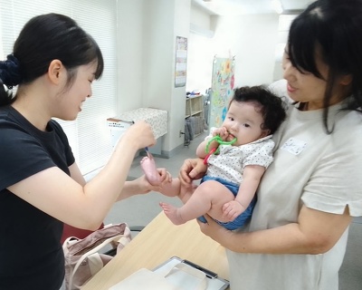 お母さんが、お子さんの足の裏に絵の具を塗っている様子
